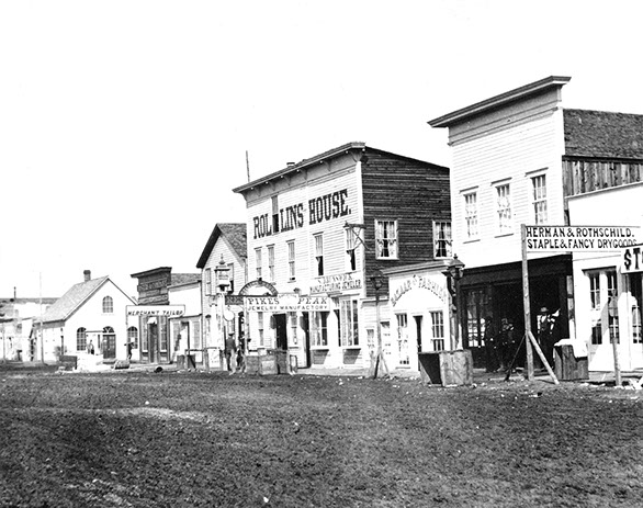 dirt road lined with two-story storefronts in black and white