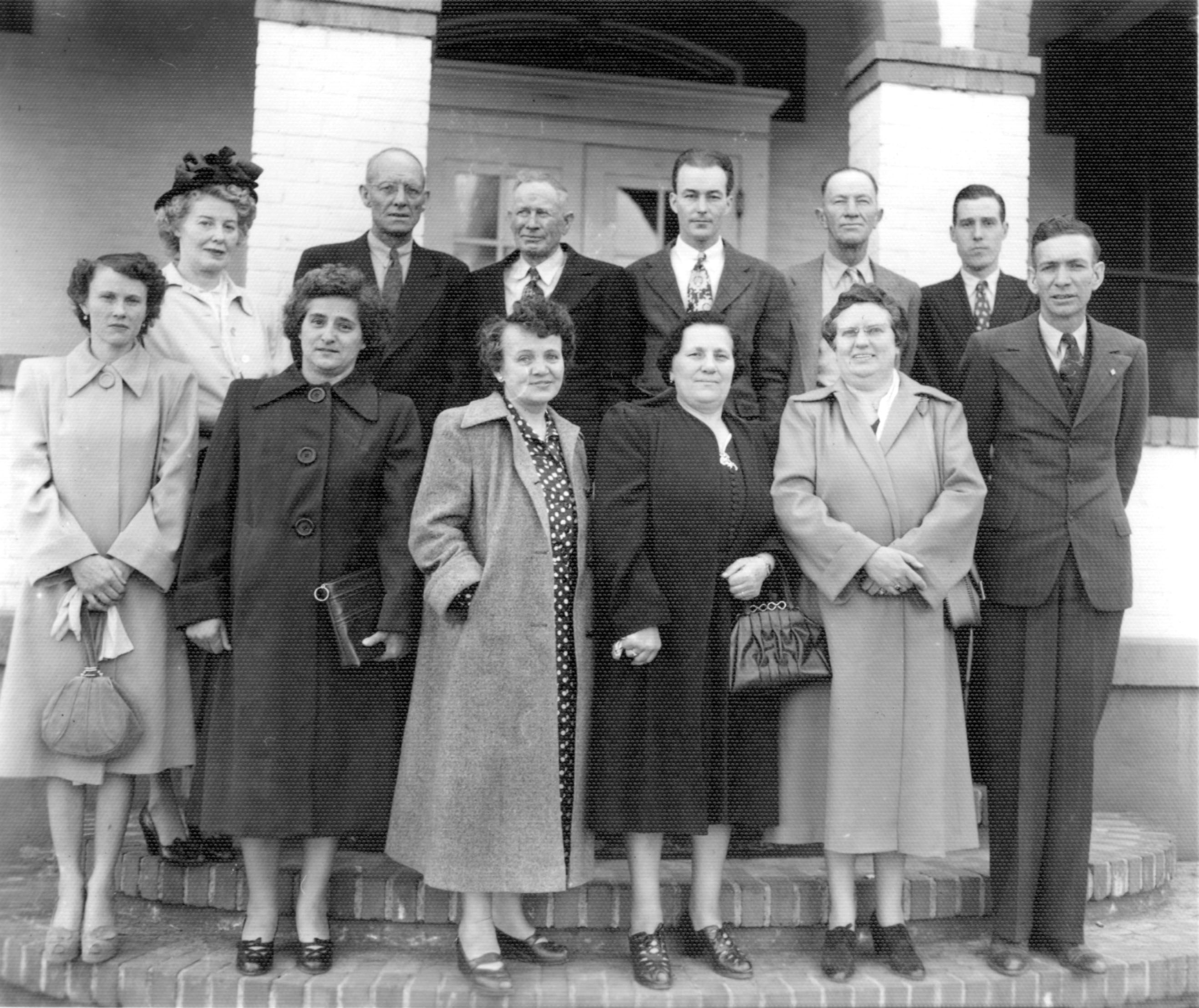 two rows of people, men and women, standing in front of a building